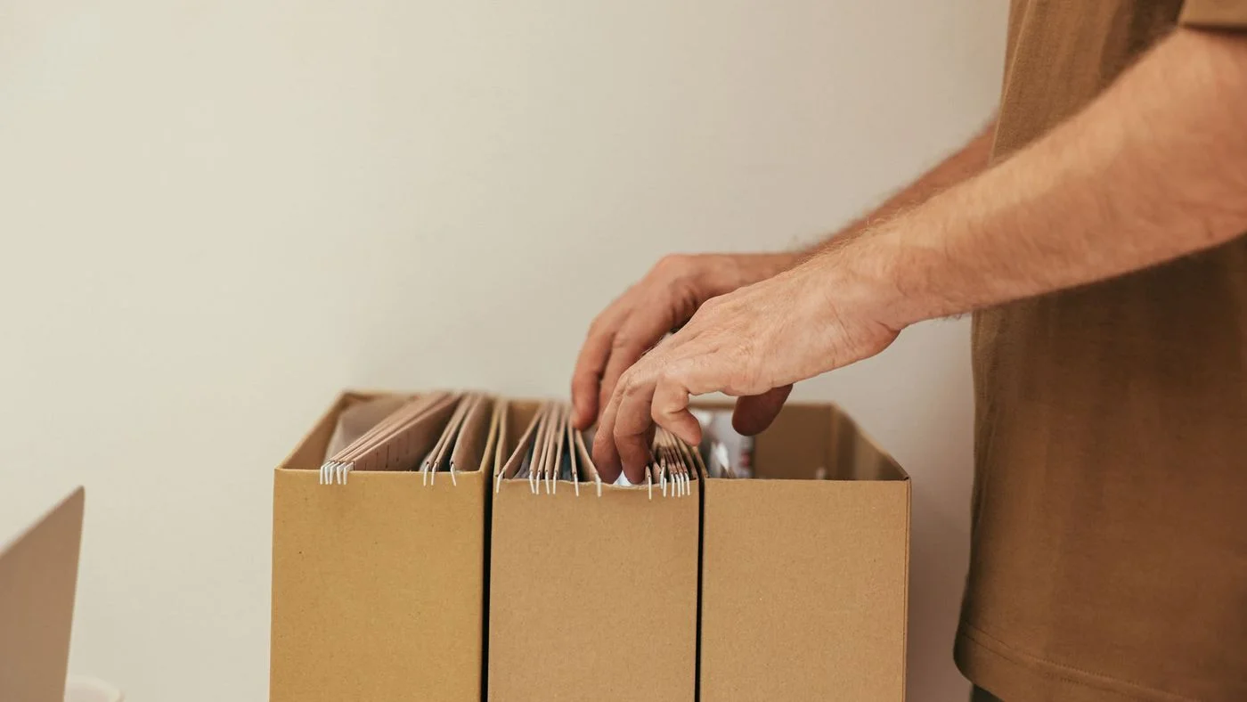 Plan de travail avec ordinateur portable, documents administratifs et cartons de dossiers