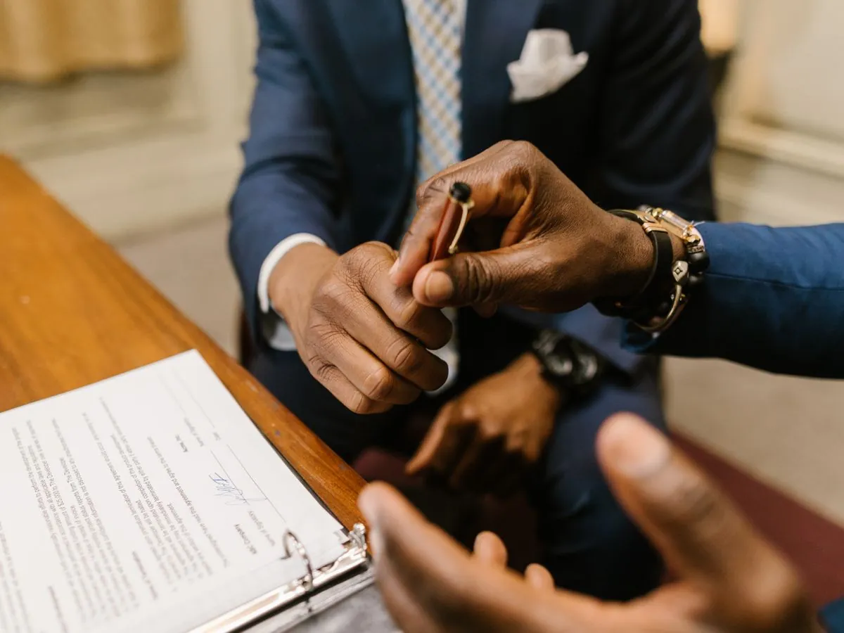 Deux professionnels en costume finalisant la signature d'un contrat sur un bureau