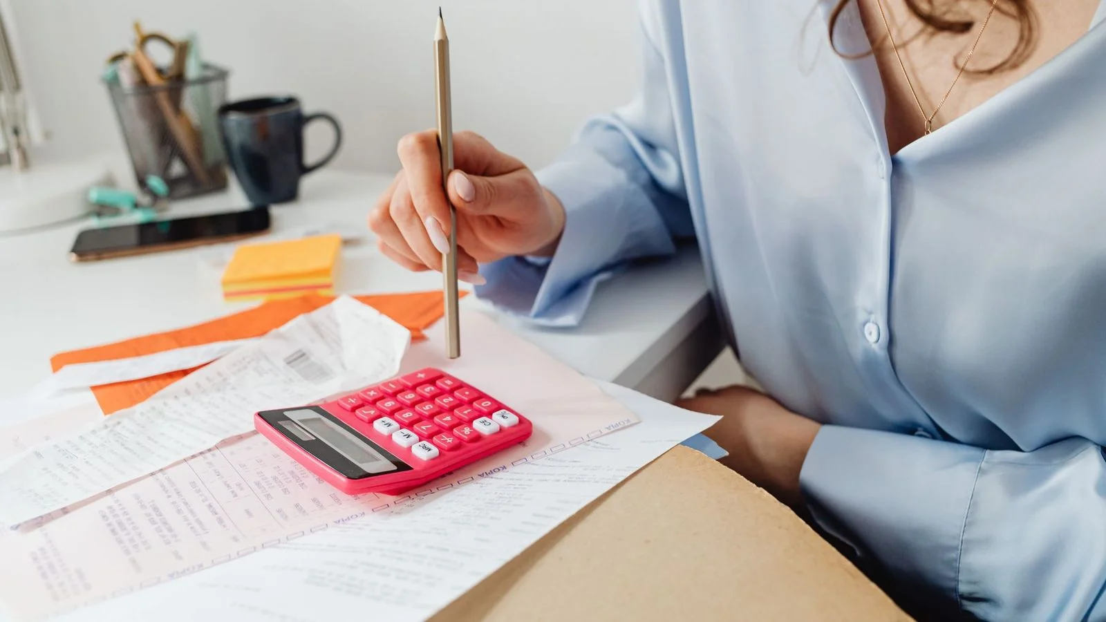 Mains d'un professionnel utilisant une calculatrice à côté d'une facture d'entreprise, illustrant le passage à la facturation électronique