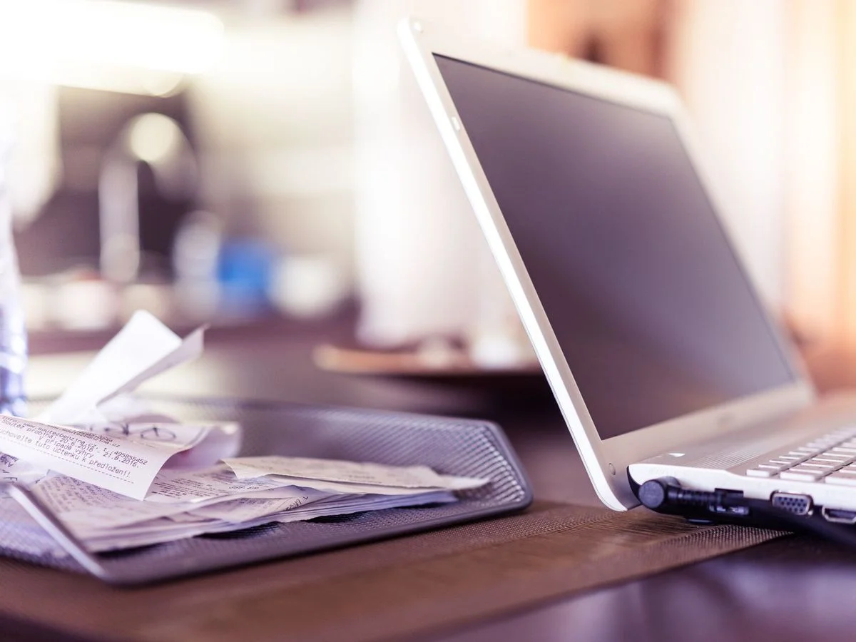 Ordinateur portable ouvert sur une table avec des documents à vérifier