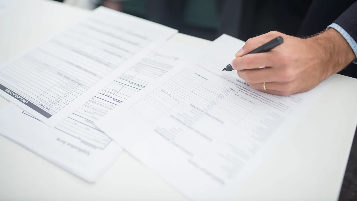 Documents administratifs et calculatrice sur un bureau, ambiance de gestion de dossier de financement