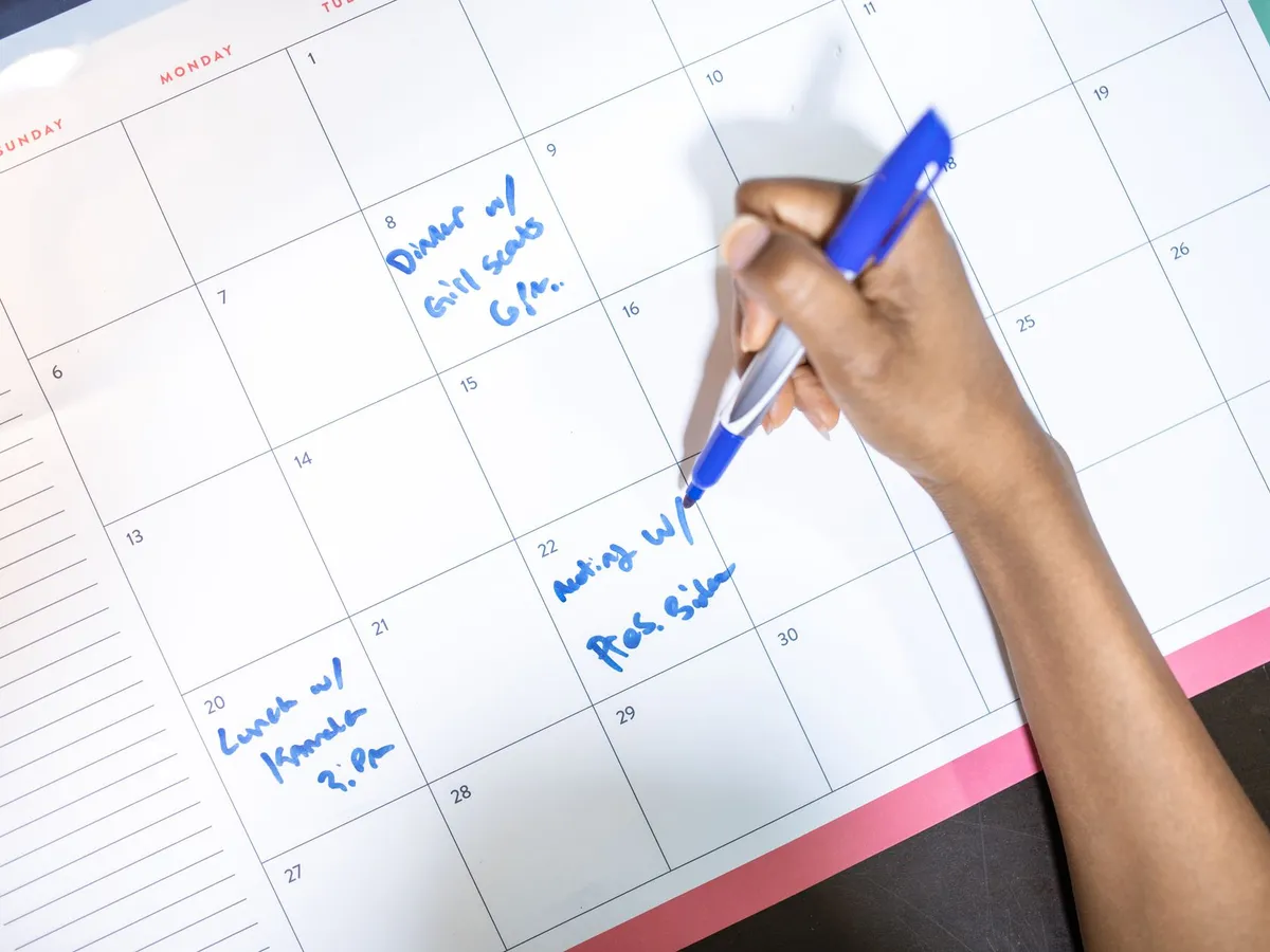 Main notant des rendez-vous de conception sur un calendrier planning