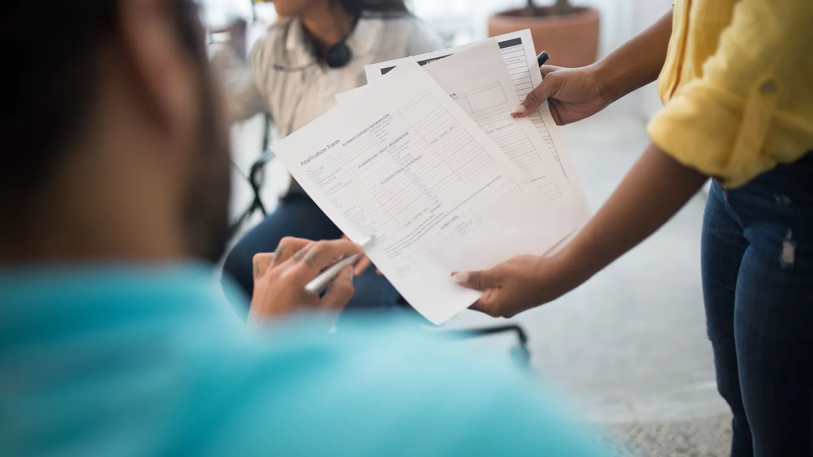 Consultant remettant un dossier de formation à des collègues lors d'un échange de documents