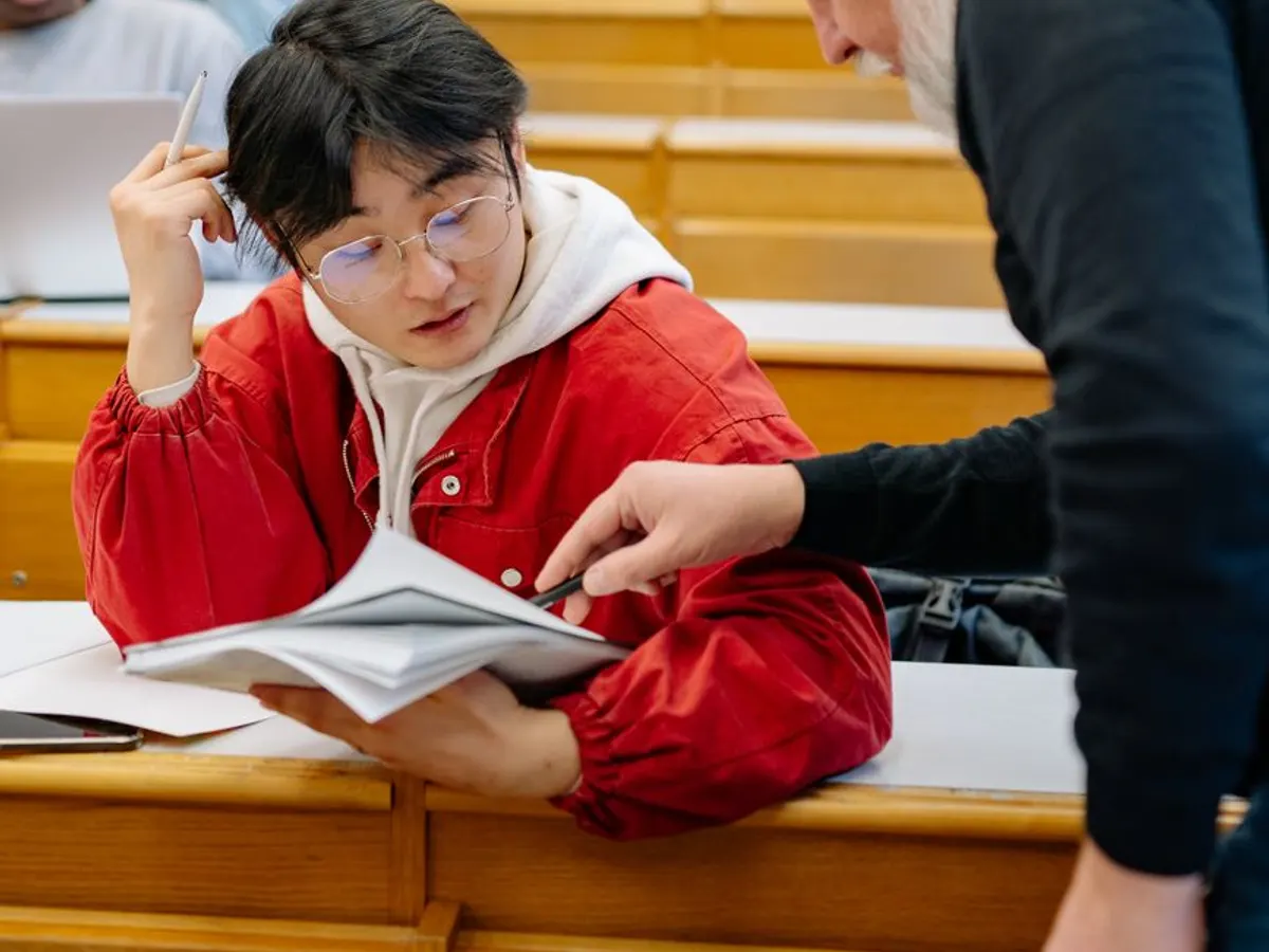Formateur accompagnant un bénéficiaire sur son support de cours en salle