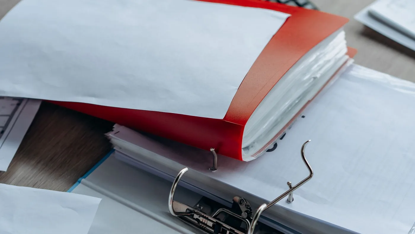 Classeurs et documents de suivi pédagogique organisés sur une étagère de bureau