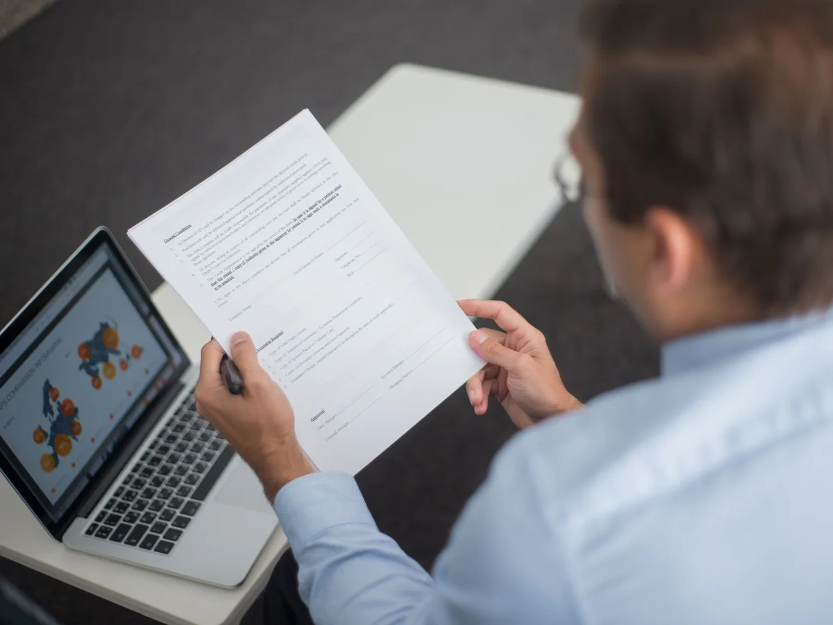 Consultant vérifiant un référentiel de certification professionnelle sur des documents et un écran