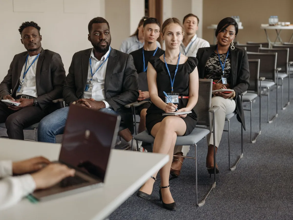 Groupe de stagiaires assis en salle de formation professionnelle, ordinateur portable au premier plan