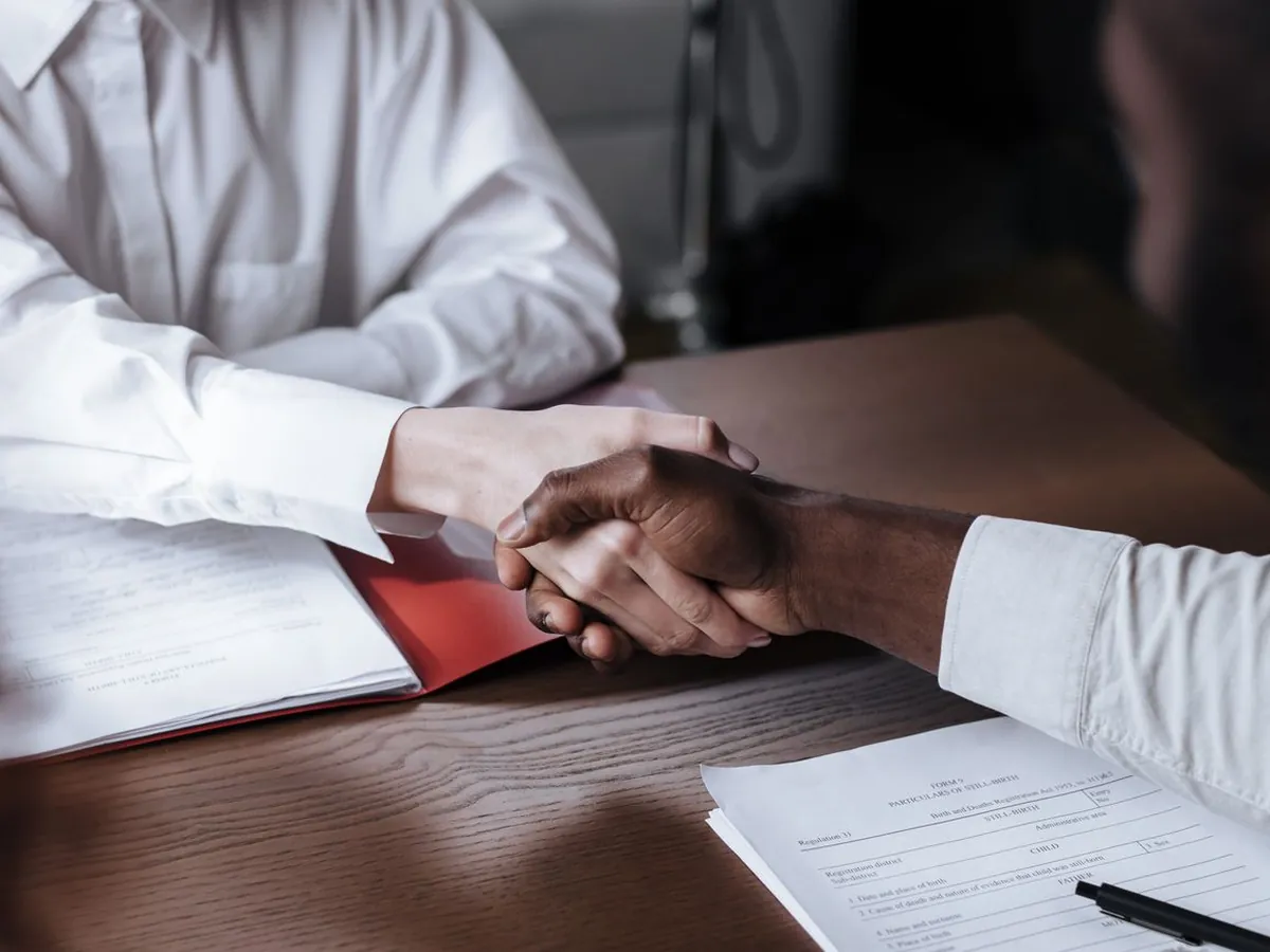 Poignée de main entre un organisme de formation donneur d'ordre et un sous-traitant au-dessus d'un dossier administratif