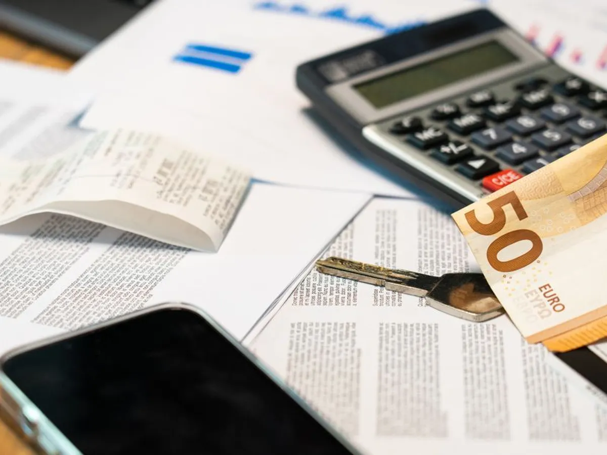 Calculatrice, billets et factures posés sur un bureau pour établir un budget