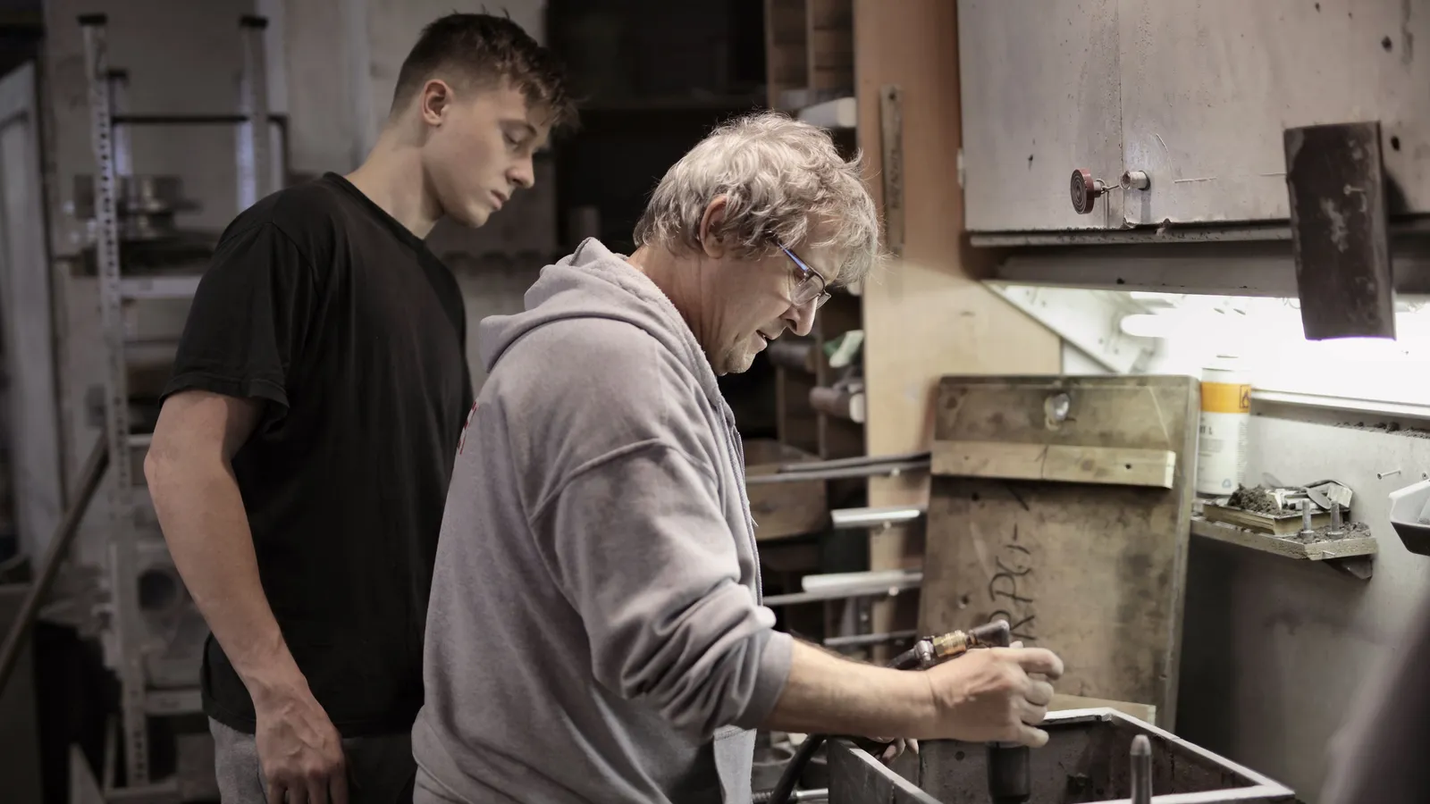 Maître d'apprentissage accompagnant un apprenti sur un poste de travail en atelier
